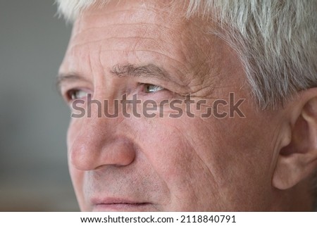Serious thoughtful senior middle aged man looking away in deep thought. Mature retiree face with brown eyes, wrinkles close up. Elderly age, healthcare, vision, eyesight concept. Cropped shot Royalty-Free Stock Photo #2118840791