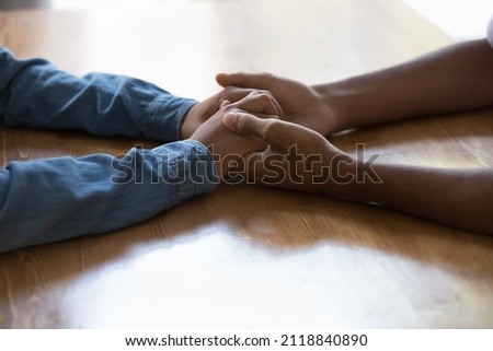 Young Black couple holding arms over table, having difficult conversation. Man touching hands of dark skinned girlfriend, giving care, love, support, compassion, empathy. Close up, cropped shot Royalty-Free Stock Photo #2118840890