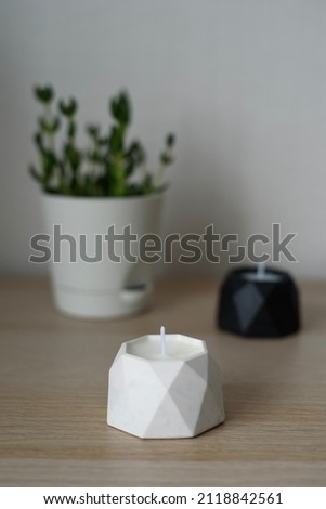 soy candles in handmade plaster candlesticks and succulent on a wooden table, close-up.