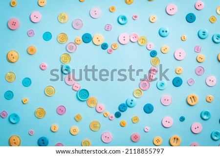 multi colored buttons heart shape on a blue paper background. Template for card, invitation. Blank space for text.