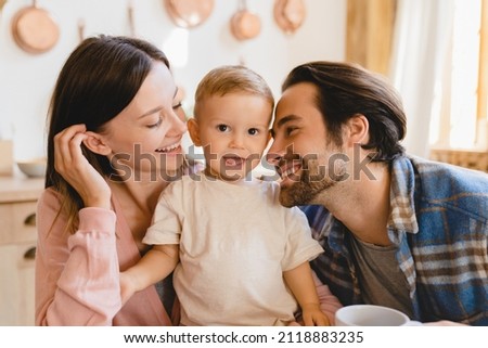 Happy family moments together. Caucasian young happy family nurturing taking care of small little kid child toddler infant baby at home kitchen. Parenthood and adoption Royalty-Free Stock Photo #2118883235