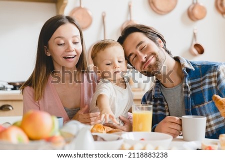 Family dinner lunch breakfast at home. Caucasian happy parents eating together, feeding small little kid child toddler new born baby infant at home kitchen. Adoption concept Royalty-Free Stock Photo #2118883238