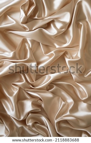Beautiful elegant wavy beige or light brown satin silk luxury cloth fabric texture, abstract background design. Card or banner