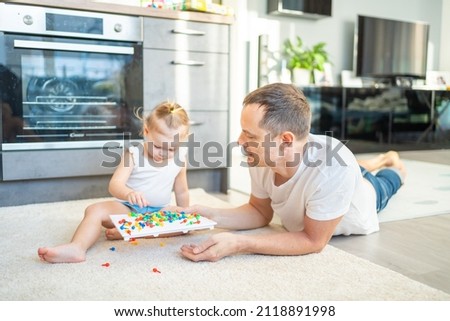 Cute little girl playing with mushroom nail mosaic. Father and baby playing together concept. Hobby and leisure time. High quality photo