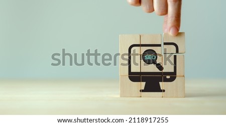 SEO, Search Engine Optimization ranking concept.  Digital marketing strategy of promote traffic to website. Hand holds wooden cubes with the icon of magnifying glass with alphabets abbreviation SEO.  Royalty-Free Stock Photo #2118917255