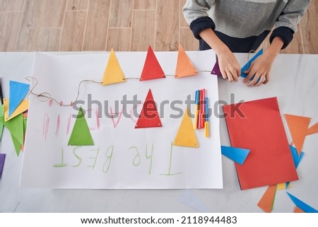 Caucasian child standing at the table and preparing holiday decor and placard for the Fathers day