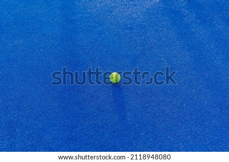 An isolated ball on a blue paddle tennis court. Racket sports concept Royalty-Free Stock Photo #2118948080