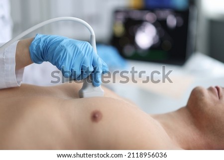 Doctor performs chest ultrasound on man in hospital closeup Royalty-Free Stock Photo #2118956036