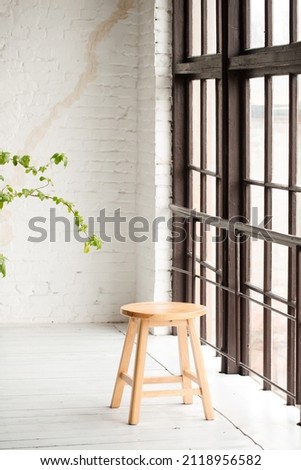 Lonely round chair by a large window in a white room