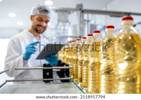 Close up view of industrial vegetable oil production and bottles filled with sunflower oil being transporter on automated conveyor machine. Royalty-Free Stock Photo #2118957794