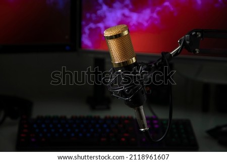 Professional microphone with gamer workstation in the background and headphones