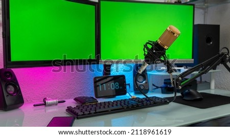 workstation with microphone and monitors with green screen for montage