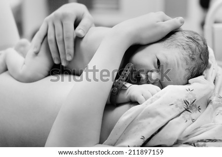 Black and white shot of newborn baby right after delivery  Royalty-Free Stock Photo #211897159
