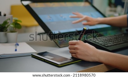 Close up of media specialist hands using graphic tablet with stylus and touch screen on monitor for photo retouching software at studio. Image editor working with retouch equipment