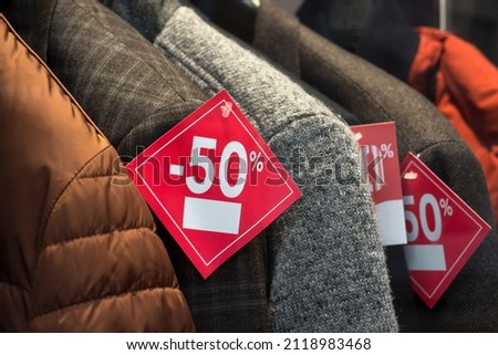 Closeup of discount signage on clothes in a fashion store showroom for men
