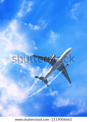 Vertical nature background with aircraft and Jet trailing smoke in the sky. Airplane and condensation trail. Foggy trail jet and plane in blue sky with white clouds. Traveling the world concept Royalty-Free Stock Photo #2119006661