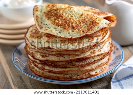 Stack of pancakes on a plate. Homemade pancakes, delicious food. Yeast pancakes are a traditional dish for the Russian Pancake week (Maslenitsa). Selective focus. Royalty-Free Stock Photo #2119011401