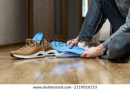 Man putting new custom insole in a shoe. Feet recreation medicine concept Royalty-Free Stock Photo #2119016153