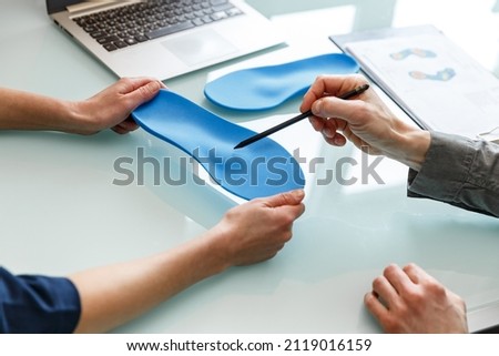 Doctor consulting patient on custom orthotic insoles in a clinic for a personalised custom fit. Feet recreation medicine concept Royalty-Free Stock Photo #2119016159