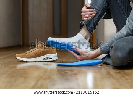 Man putting new custom insole in a shoe. Feet recreation medicine concept Royalty-Free Stock Photo #2119016162