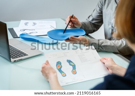 Doctor consulting patient on custom orthotic insoles in a clinic for a personalised custom fit. Feet recreation medicine concept Royalty-Free Stock Photo #2119016165