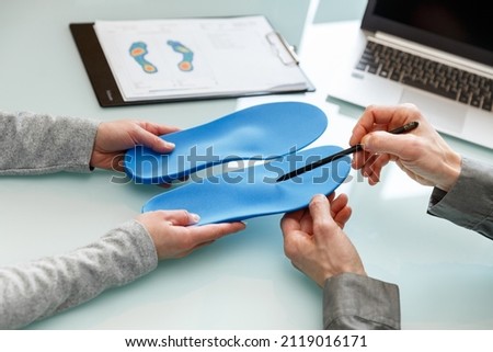 Doctor consulting patient on custom orthotic insoles in a clinic for a personalised custom fit. Feet recreation medicine concept Royalty-Free Stock Photo #2119016171