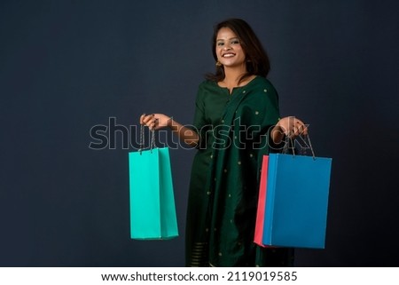 Beautiful Indian young girl or woman holding and posing with shopping bags on a dark background