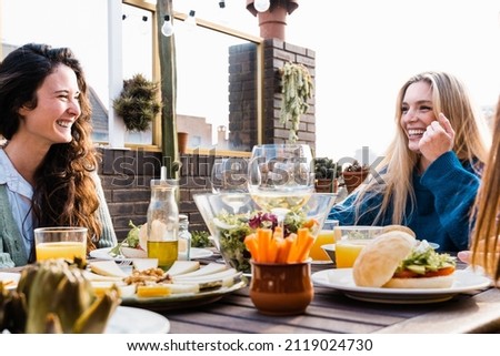 Happy people eating vegan food dinner outdoor at patio restaurant - Focus on right girl face