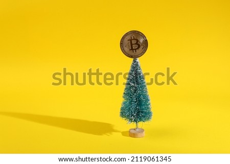 Mini Christmas tree with bitcoin on a yellow background. Minimal financial layout