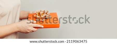 Close up shot of woman hands holding surprise gift package box on pink pastel background with copy space. Valentine's gift