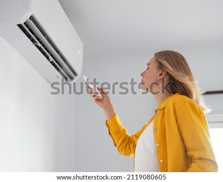 Women dying from the heat standing in front of the air conditioner. Royalty-Free Stock Photo #2119080605