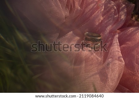 wedding rings on pink fabric green background bokeh blurry