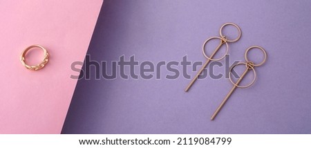 Top view of geometric modern earrings and ring on pastel colors background