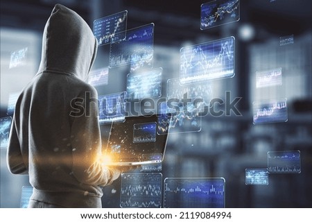 Hacker in hoodie using laptop with various forex screens on blurry office interior background. Cryptocurrency, hacking, bticoin trading and finance concept. Double exposure