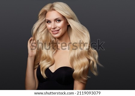 Beautiful blond girl with a perfectly curls hair, and classic make-up. Beauty face and hair.
