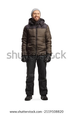 Full length portrait of a man in a winter jacket and pants standing isolated on white background
