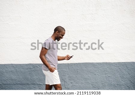 Profile portrait african american mania t-shirt and shorts walking with cellphone 