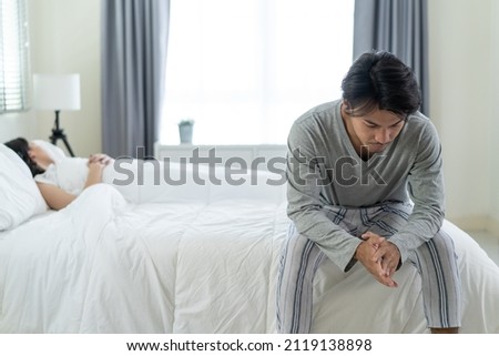 Asian young man feel angry girlfriend having conflict domestic problem. New marriage man and woman feel heartbroken for quarrel conflict while sit on bed in bedroom. Family problem-separation concept. Royalty-Free Stock Photo #2119138898