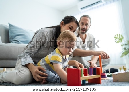 Caucasian happy loving parent play with baby toddler in living room. Attractive couple mother and father spend time with young little infant son child in house. Activity relationship at home concept. Royalty-Free Stock Photo #2119139105