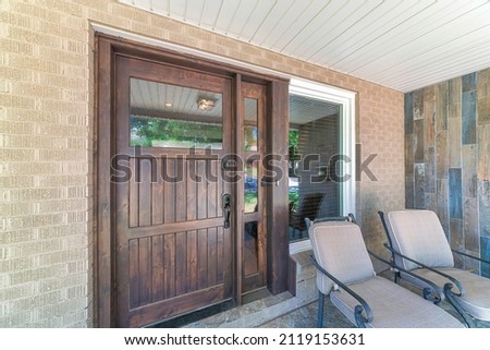Dark wood front door with glass panel and sidelight near the picture window