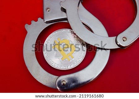 Bitcoin and handcuffs over red background