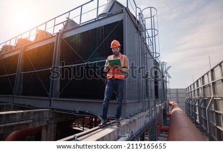 Industry engineer under checking the industry cooling tower air conditioner is water cooling tower air chiller HVAC of large industrial building to control air system. Royalty-Free Stock Photo #2119165655