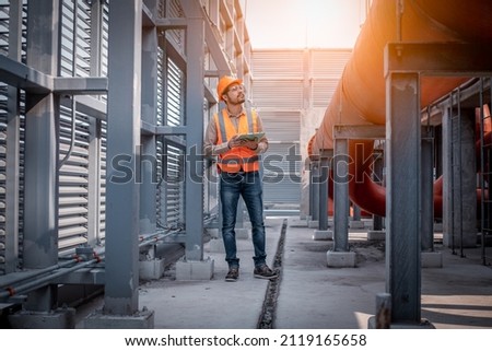 Industry engineer under checking the industry cooling tower air conditioner is water cooling tower air chiller HVAC of large industrial building to control air system. Royalty-Free Stock Photo #2119165658