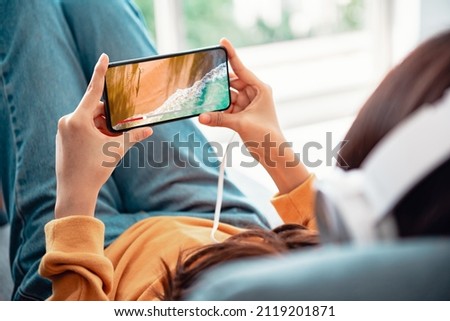 Online movie stream with smartphone. Woman watching film on mobile phone with imaginary video player service.