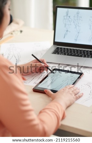Fashion designer drawing sketches on tablet computer when working on collection for new season