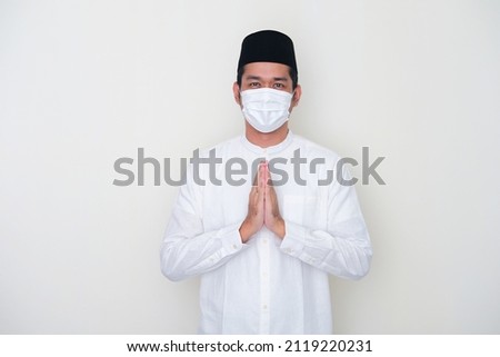 Moslem Asian man greeting pose and wearing medical mask to celebrate Ramadan during pandemic Royalty-Free Stock Photo #2119220231