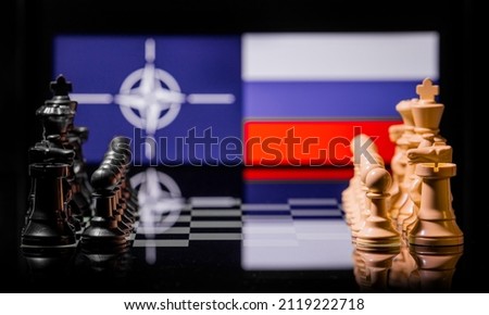 Conceptual image of war between Russia and NATO using chess pieces and national flags on a reflective background