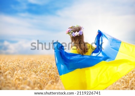 Pray for Ukraine. Child with Ukrainian flag in wheat field. Little girl waving national flag praying for peace. Happy kid celebrating Independence Day. Royalty-Free Stock Photo #2119226741