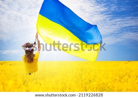 Pray for Ukraine. Child with Ukrainian flag in a field of yellow flowers. Little girl waving national flag praying for peace. Happy kid celebrating Independence Day. Royalty-Free Stock Photo #2119226828