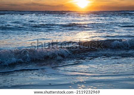 Sunset over the beach of Roche in Conil de la Frontera, waves breaking on the shore of sandy marvelous beach